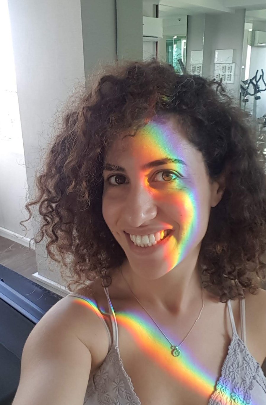 Tamar Shoker smiling, with a rainbow of light across her face